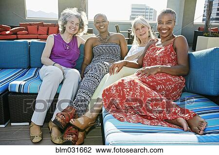 Stock Image - Women relaxing together on urban rooftop. Fotosearch