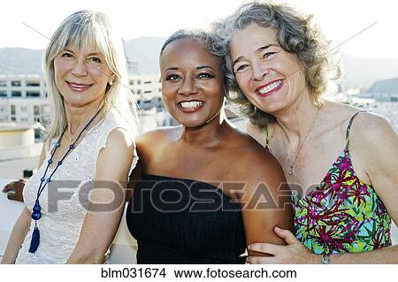 Picture - Women smiling together on urban rooftop. Fotosearch