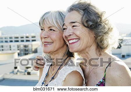 Stock Image - Women smiling together on urban rooftop. Fotosearch