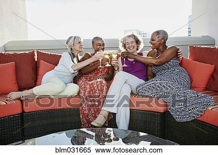 Stock Photography - Women toasting each other with wine on urban rooftop. Fotosearch