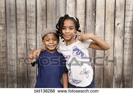 Stock Photo - African American brother and sister hugging near wooden fence. Fotosearch