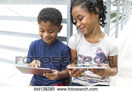 Stock Photo - African American brother and sister using digital tablets. Fotosearch