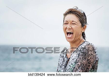Asian woman laughing near ocean View Large Photo Image Picture - Asian woman laughing near ocean. Fotosearch