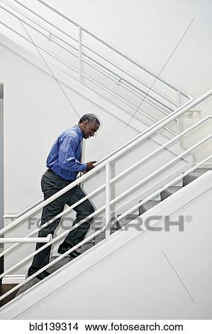 Picture - Black businessman climbing staircase. Fotosearch