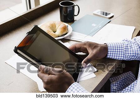 Stock Image - Black businessman using digital tablet in cafe. Fotosearch