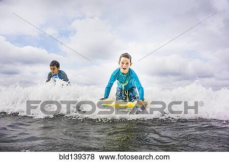 Boys surfing together in waves View Large Photo Image Stock Photo - Boys surfing together in waves. Fotosearch