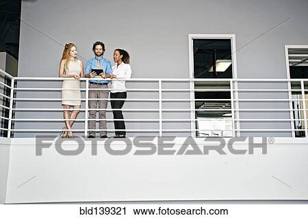 Stock Image - Business people using digital tablet at railing. Fotosearch