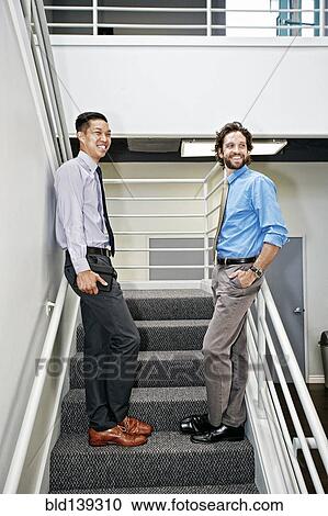 Stock Image - Businessmen standing on staircase. Fotosearch