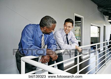 Businessmen talking at railing View Large Photo Image Stock Image - Businessmen talking at railing. Fotosearch