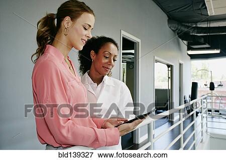 Stock Photo - Businesswoman and doctor using digital tablet at railing. Fotosearch