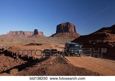 Stock Image - Car driving on remote road through rock formations, Monument Valley Tribal Park, Utah, United States. Fotosearch