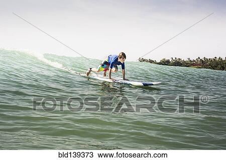 Stock Image - Caucasian boy surfing in ocean. Fotosearch