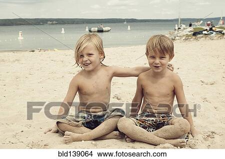 Picture - Caucasian brothers hugging on beach. Fotosearch