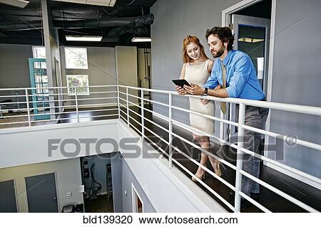 Stock Image - Caucasian business people using digital tablet at railing, . Fotosearch