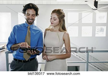 Stock Photo - Caucasian business people using digital tablet near staircase. Fotosearch