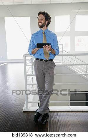 Caucasian businessman using digital tablet near staircase View Large Photo Image Stock Photo - Caucasian businessman using digital tablet near staircase. Fotosearch