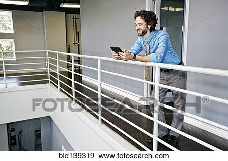 Caucasian businessman using digital tablet at railing View Large Photo Image Stock Photo - Caucasian businessman using digital tablet at railing. Fotosearch