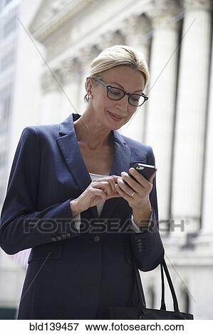 Stock Photo - Caucasian businesswoman using cell phone in city street, New York City, New York, United States. Fotosearch