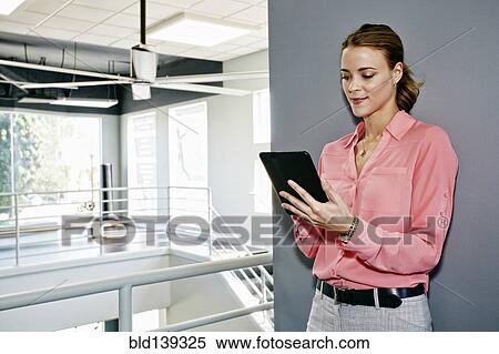 Stock Photography - Caucasian businesswoman using digital tablet near railing. Fotosearch
