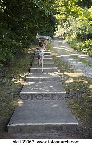 Stock Image - Caucasian children climbing stairs near rural path. Fotosearch