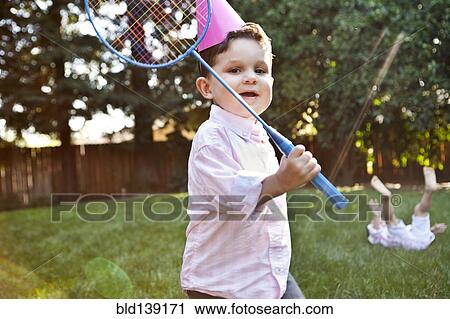 Stock Image - Caucasian children playing badminton in backyard. Fotosearch