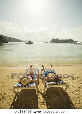 Caucasian couple holding hands in deck chairs on beach View Large Photo Image Stock Photograph - Caucasian couple holding hands in deck chairs on beach. Fotosearch