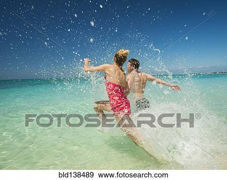 Caucasian couple splashing in waves in tropical ocean View Large Photo Image Stock Photo - Caucasian couple splashing in waves in tropical ocean. Fotosearch