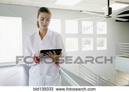 Stock Image - Caucasian doctor using digital tablet near railing, . Fotosearch