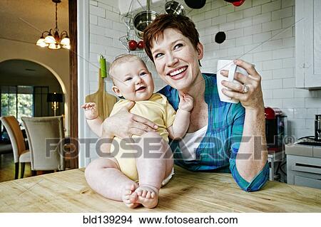 Caucasian mother and baby relaxing in kitchen View Large Photo Image Picture - Caucasian mother and baby relaxing in kitchen. Fotosearch