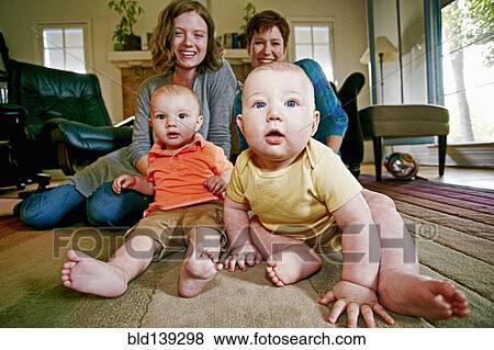 Stock Photo - Caucasian mothers and babies sitting on living room floor. Fotosearch