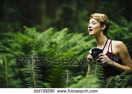 Caucasian woman holding camera in forest View Large Photo Image Stock Image - Caucasian woman holding camera in forest. Fotosearch