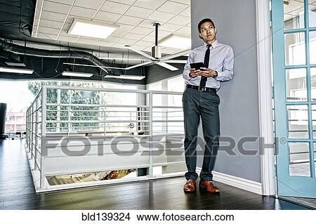 Picture - Chinese businessman using digital tablet outside office. Fotosearch