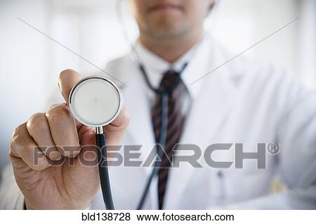 Stock Photo - Close up of mixed race doctor holding stethoscope. Fotosearch
