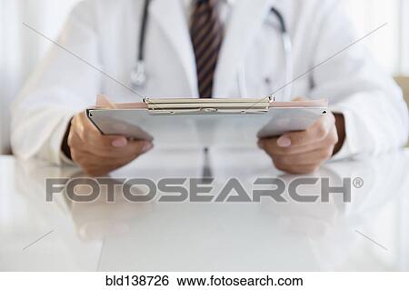Close up of mixed race doctor holding clipboard View Large Photo Image Stock Photograph - Close up of mixed race doctor holding clipboard. Fotosearch