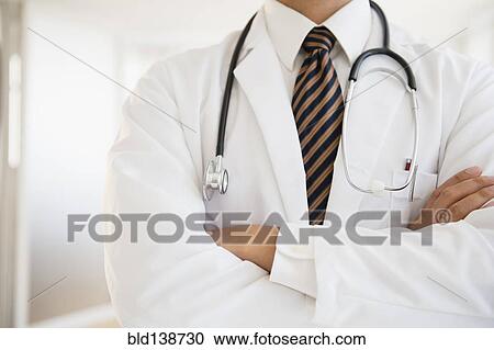 Stock Image - Close up of mixed race doctor with arms crossed. Fotosearch