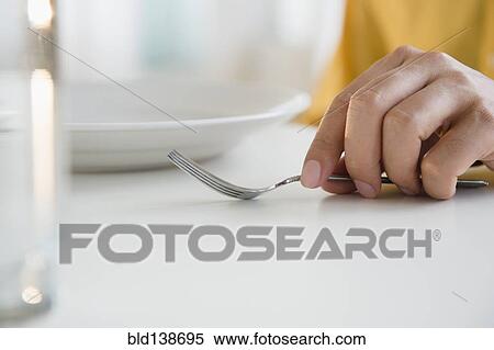 Stock Photography - Close up of mixed race man holding fork at table. Fotosearch