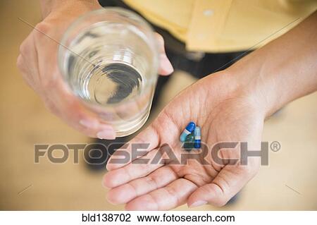 Close up of mixed race man holding medicine and glass of water View Large Photo Image Stock Image - Close up of mixed race man holding medicine and glass of water. Fotosearch