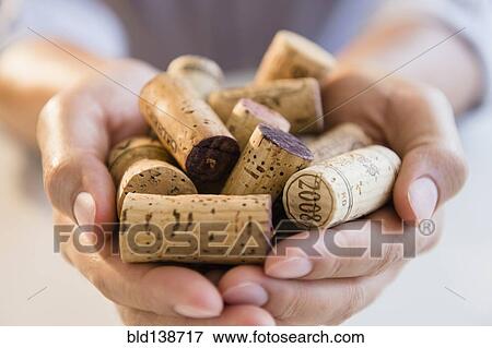 Stock Photo - Close up of mixed race man holding wine corks. Fotosearch
