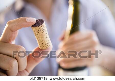 Stock Photo - Close up of mixed race man holding wine cork. Fotosearch