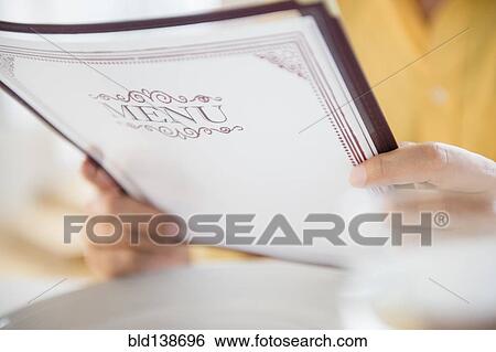 Stock Photograph - Close up of mixed race man reading menu in restaurant. Fotosearch