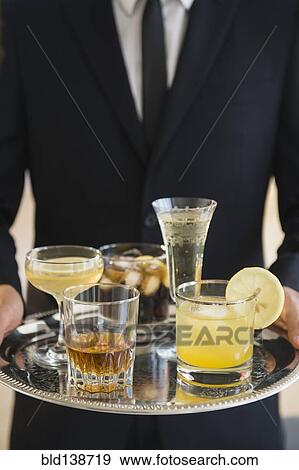 Stock Photo - Close up of mixed race waiter holding tray of drinks. Fotosearch