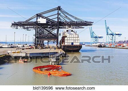 Stock Photograph - Cranes over cargo ship in harbor. Fotosearch