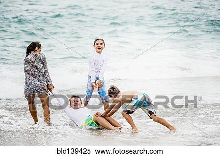 Family playing together in waves on beach View Large Photo Image Stock Photography - Family playing together in waves on beach. Fotosearch