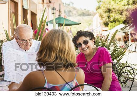 Stock Image - Family reading menu at sidewalk cafe. Fotosearch