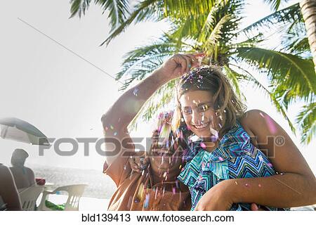 Stock Image - Father and daughter playing with confetti outdoors. Fotosearch