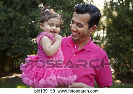 Stock Photo - Father holding daughter in backyard. Fotosearch