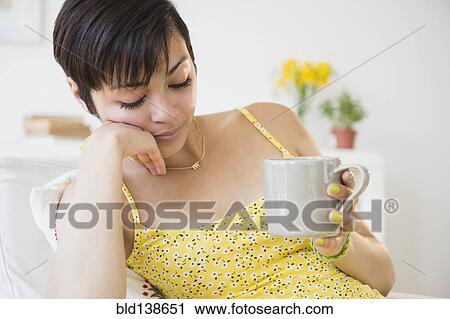 Fatigued mixed race woman drinking cup of coffee View Large Photo Image Stock Image - Fatigued mixed race woman drinking cup of coffee. Fotosearch
