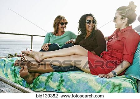 Friends relaxing together at waterfront View Large Photo Image Stock Image - Friends relaxing together at waterfront. Fotosearch