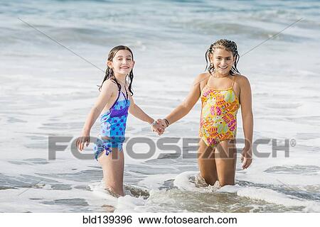 Girls holding hands in ocean waves View Large Photo Image Stock Photograph - Girls holding hands in ocean waves. Fotosearch