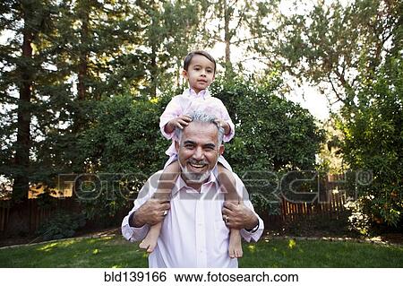 Grandfather carrying grandson on shoulders in backyard View Large Photo Image Stock Photograph - Grandfather carrying grandson on shoulders in backyard. Fotosearch